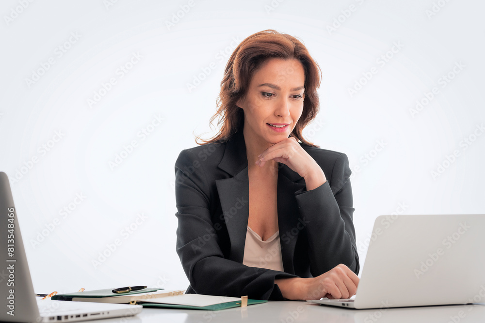 Mid age businesswoman sitting at desk and using laptop against isolated background Mid age businesswoman sitting at desk and using laptop against isolated background