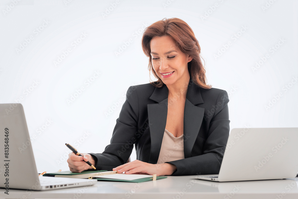 Mid age businesswoman sitting at desk and using laptop against isolated background Mid age businesswoman sitting at desk and using laptop against isolated background