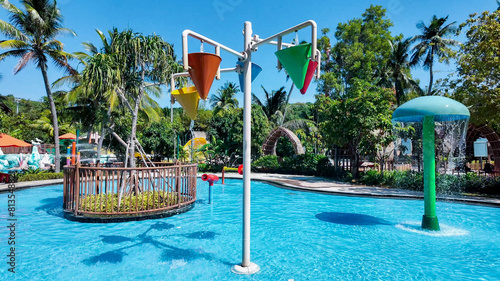 Sunny day at a tropical water park featuring colorful tipping buckets and a sprinkler mushroom, ideal for summer and family vacation concepts
