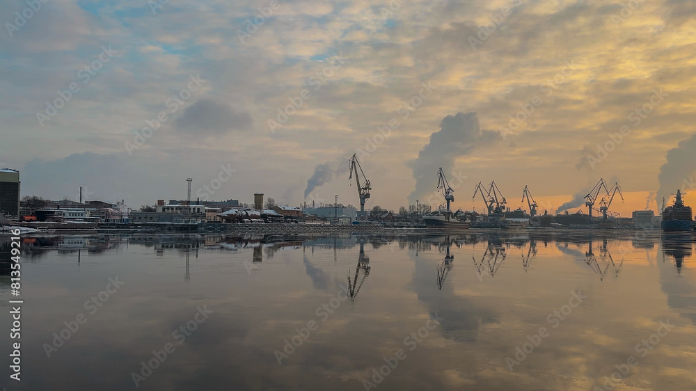 Tranquil sunrise at an industrial port with cargo cranes reflecting in calm waters, suitable for themes of global trade, logistics, and Labor Day