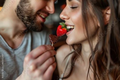 A couple feeding each other strawberries dipped in chocolate