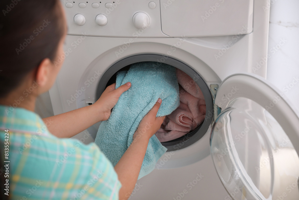 Woman putting dirty laundry into washing machine indoors, closeup Woman putting dirty laundry into washing machine indoors, closeup