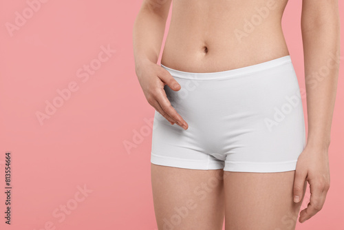 Woman holding hand near panties on pink background, space for text. Women's health