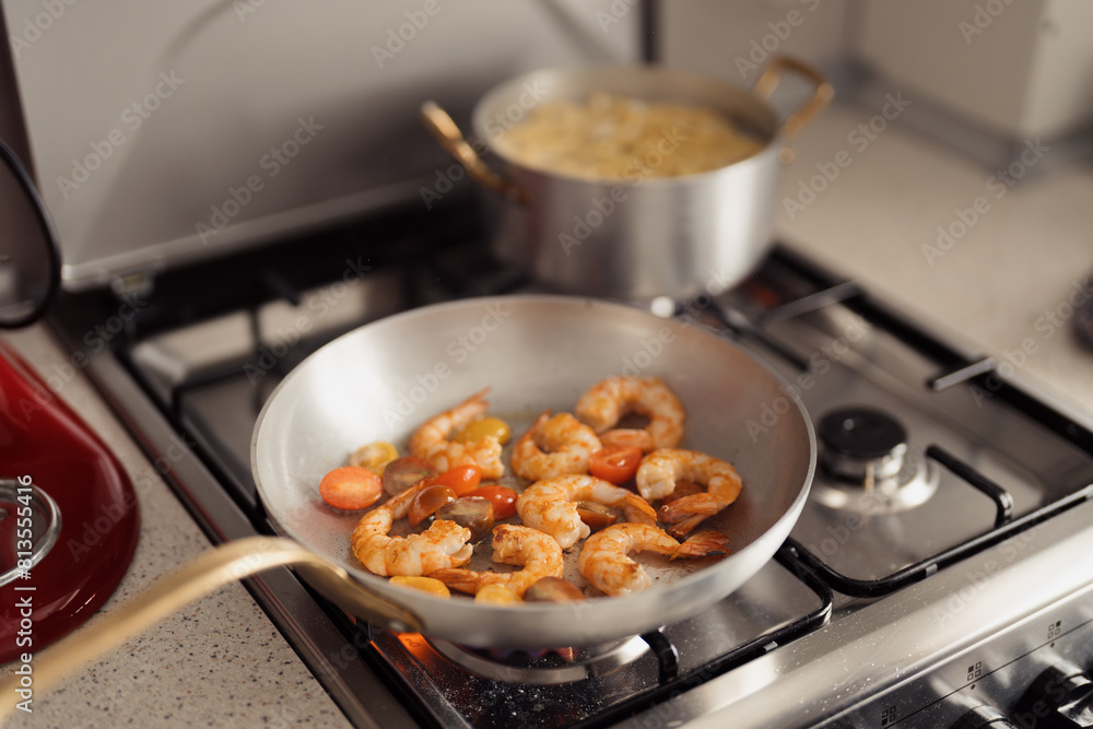 Shrimp being sauteed with tomatoes in a modern kitchen setting. Shrimp being sauteed with tomatoes in a modern kitchen setting.