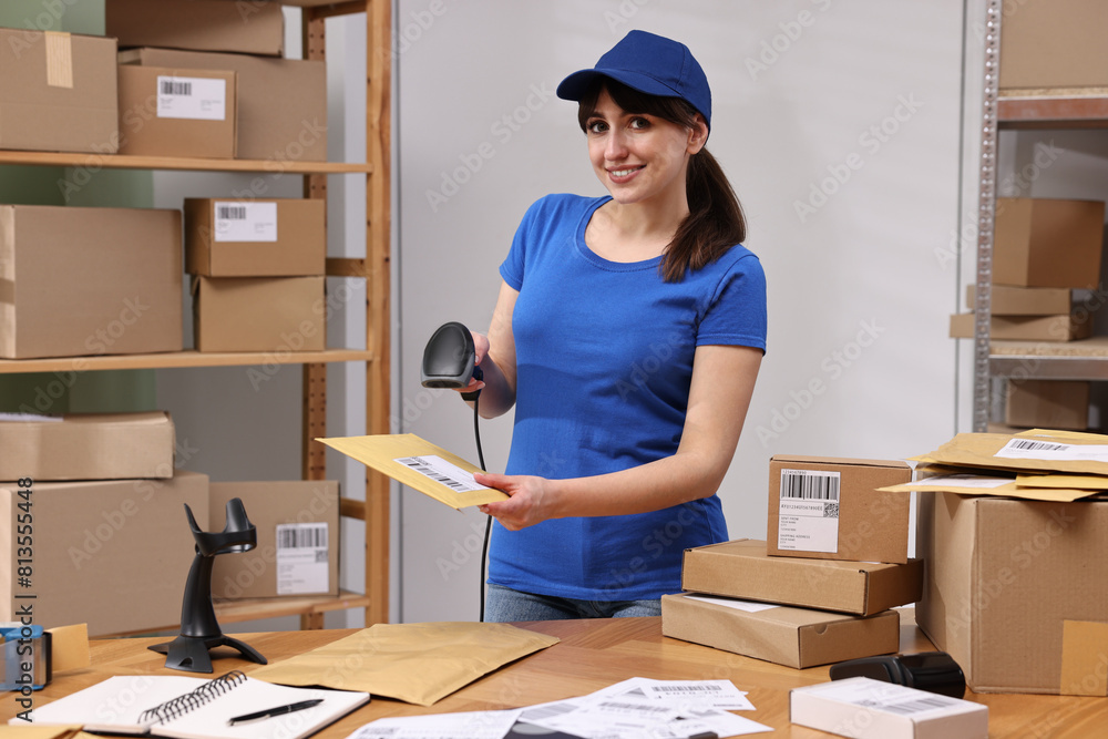 Parcel packing. Post office worker with scanner reading barcode at wooden table indoors Parcel packing. Post office worker with scanner reading barcode at wooden table indoors