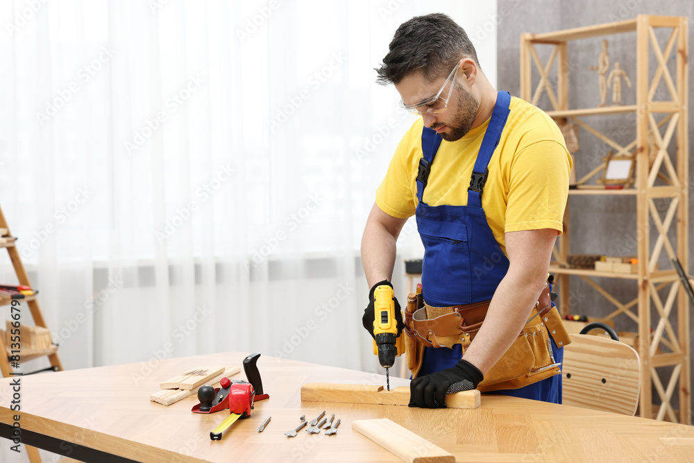 Young worker using electric drill at table in workshop Young worker using electric drill at table in workshop