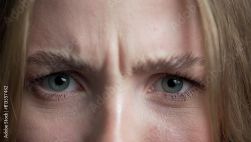 Close-up of female face frowning. Girl with blue eyes looking at camera. Concept of anger and skepticism.