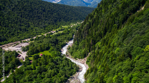 Aerial view of a winding river cutting through a lush green mountain forest, showcasing nature, environment, and Earth Day concept