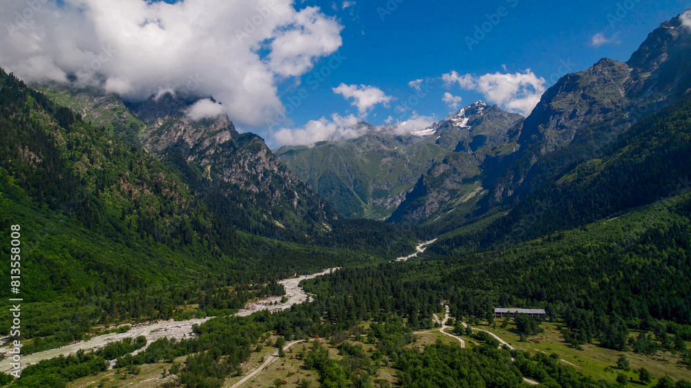 Breathtaking panoramic view of vibrant green meadows leading to snow-capped peaks under a blue sky, ideal for nature and travel themes, Earth Day promotions