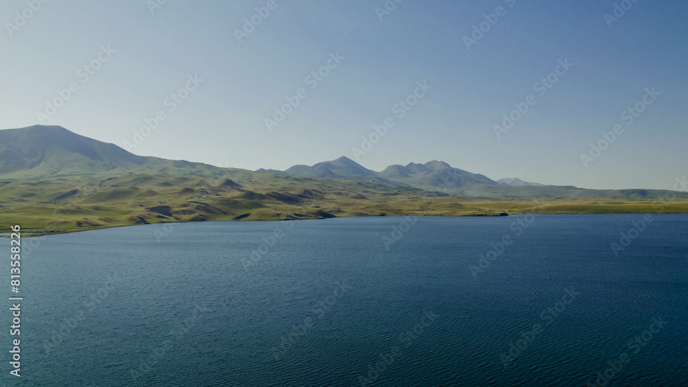 Serene lake landscape with clear blue waters and rolling hills under a sunny sky, ideal for themes of tranquility, nature, and Earth Day