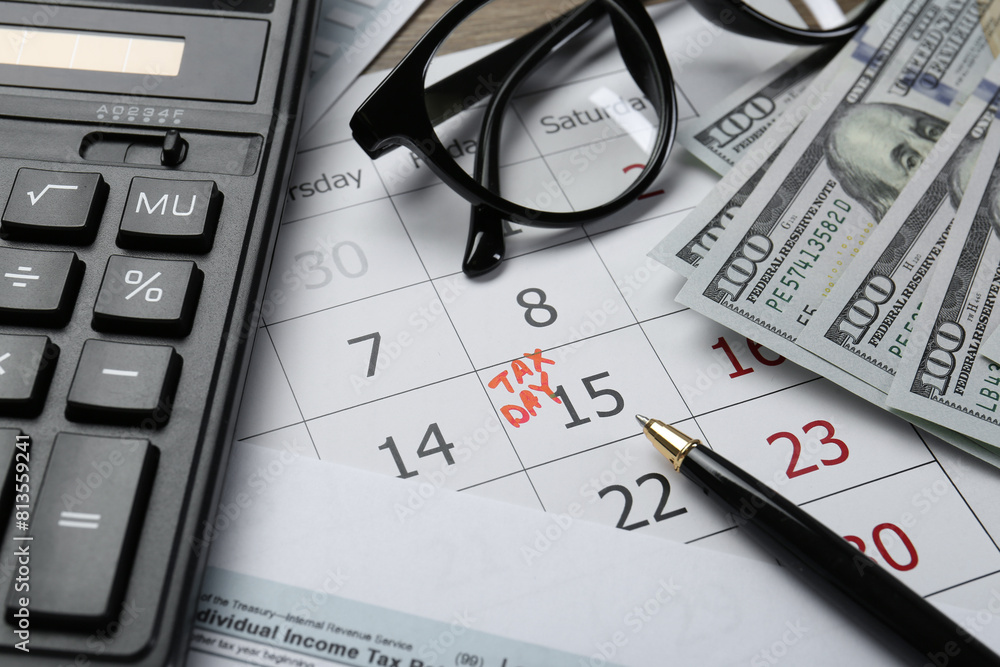 Fototapeta premium Calendar with date reminder about tax day, documents, money, pen, calculator and glasses on table, closeup