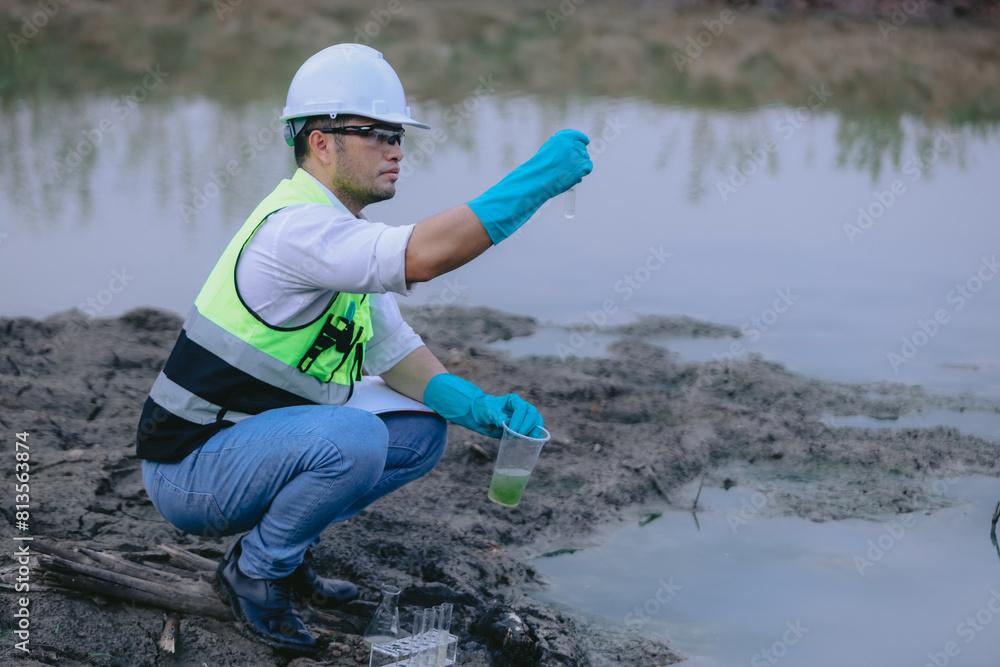 Asian man ecologist holds magnifying glass to inspect water in transparent glass at the lake. Concept, explore, analysis water quality and creature from natural source. Ecology field research. Asian man ecologist holds magnifying glass to inspect water in transparent glass at the lake. Concept, explore, analysis water quality and creature from natural source. Ecology field research.