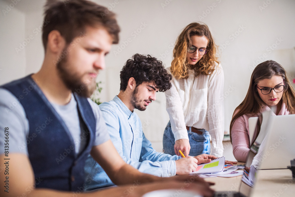 Young group of colleagues working on a new project together in a startup company office. Working in co-working space. Young group of colleagues working on a new project together in a startup company office. Working in co-working space.