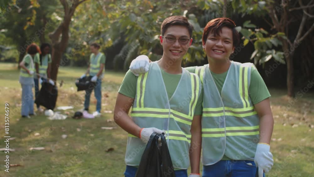 Medium portrait of male Asian friends posing for camera when volunteering in local city park Medium portrait of male Asian friends posing for camera when volunteering in local city park