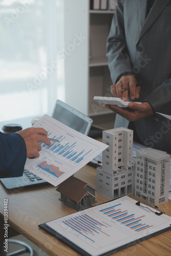 balancing the property sector The real estate agent is explaining the house style to see the house design and the purchase agreement.Wooden house at modern office