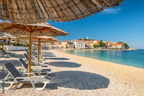 An empty beach with sun umbrellas and vacant sunbeds on the Primosten beach, Croatia