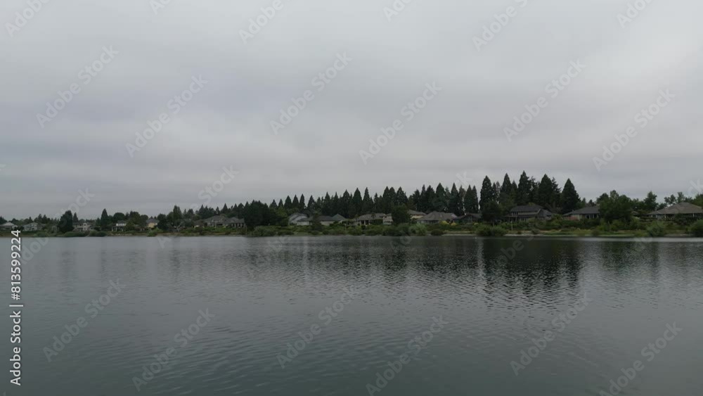 Drone shot around a lake and houses near with trees in the background Drone shot around a lake and houses near with trees in the background