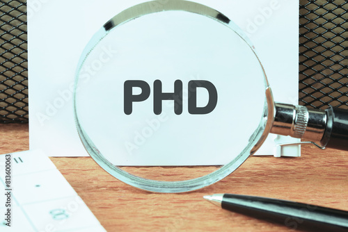 Word PhD. Doctor of Philosophy. PHD through a magnifying glass on a white sheet photo