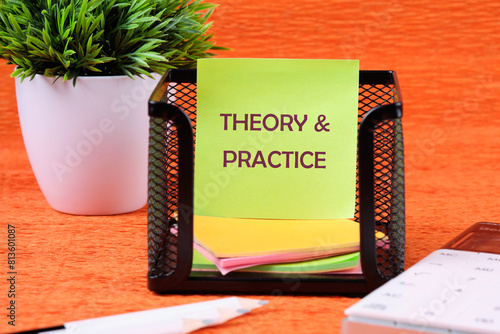 Business, theory and practice concept. Copy space. Theory and practice symbol on a sticker on a stand near a calculator, pencils and a green plant in the background