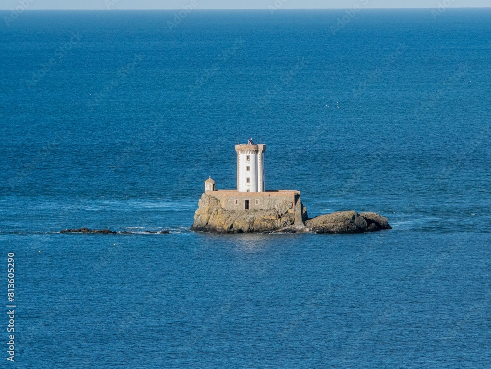 Aerial view of Phare de L'Ost-Pic lighthouse in the middle of clear blue sea in France Aerial view of Phare de L'Ost-Pic lighthouse in the middle of clear blue sea in France