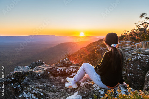 Young woman sitting on edge of Reed Lookout cliff while enjoying sunset in Grampians mountains, Victoria, Australia © myphotobank.com.au
