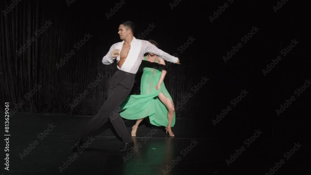 Ballroom couple performs expressive dance sequence, man jerkily turns girl around in semi-circle, she throws her leg into Grand Rond De Jambe, bypasses her partner from behind and walks off into Ballroom couple performs expressive dance sequence, man jerkily turns girl around in semi-circle, she throws her leg into Grand Rond De Jambe, bypasses her partner from behind and walks off into