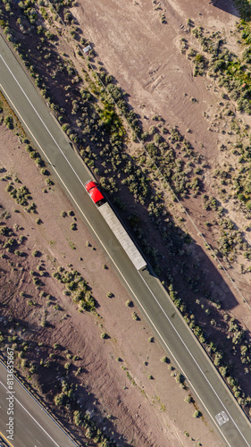 A big truck is driving on an American highway in the middle of the desert. View from a height. View from a drone