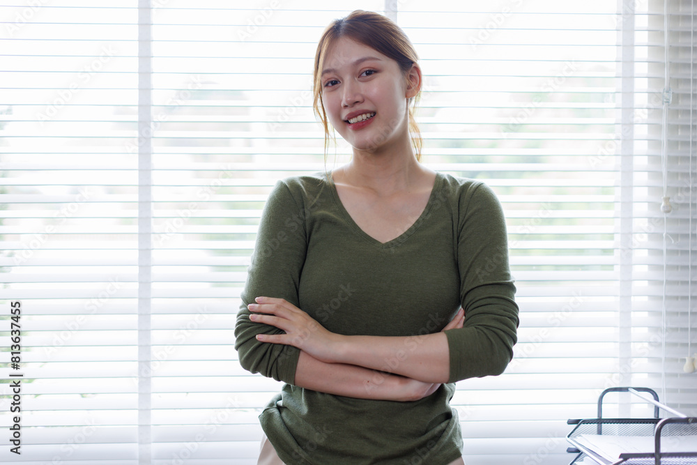 Young Asian business woman smiling confidently while standing alone in a bright modern office Young Asian business woman smiling confidently while standing alone in a bright modern office