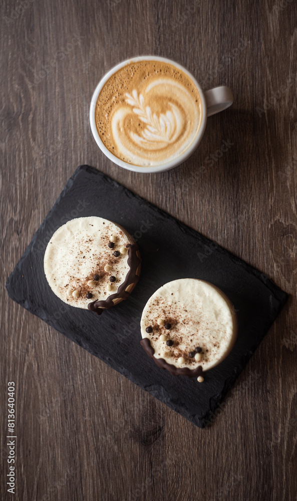 three-layer mousse dessert with chocolate and chocolate chips and crispy balls on a black stone board on a wooden table, close-up with cappuccino in a white cup top view. food photography, sweets.
three-layer mousse dessert with chocolate and chocolate chips and crispy balls on a black stone board on a wooden table, close-up with cappuccino in a white cup top view. food photography, sweets.