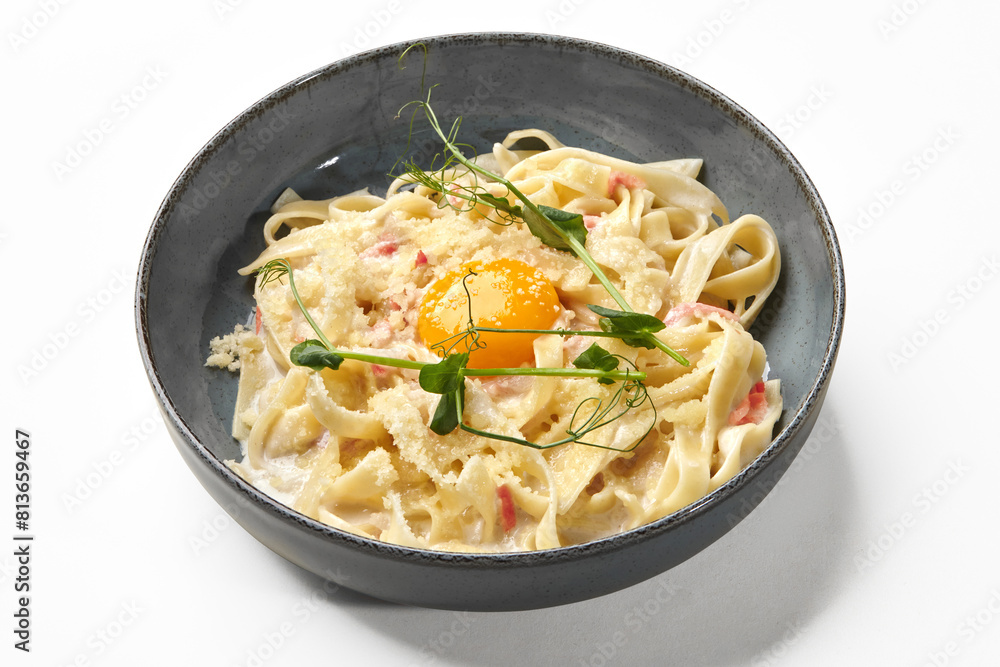 Creamy fettuccine carbonara with pancetta and egg yolk on white Creamy fettuccine carbonara with pancetta and egg yolk on white