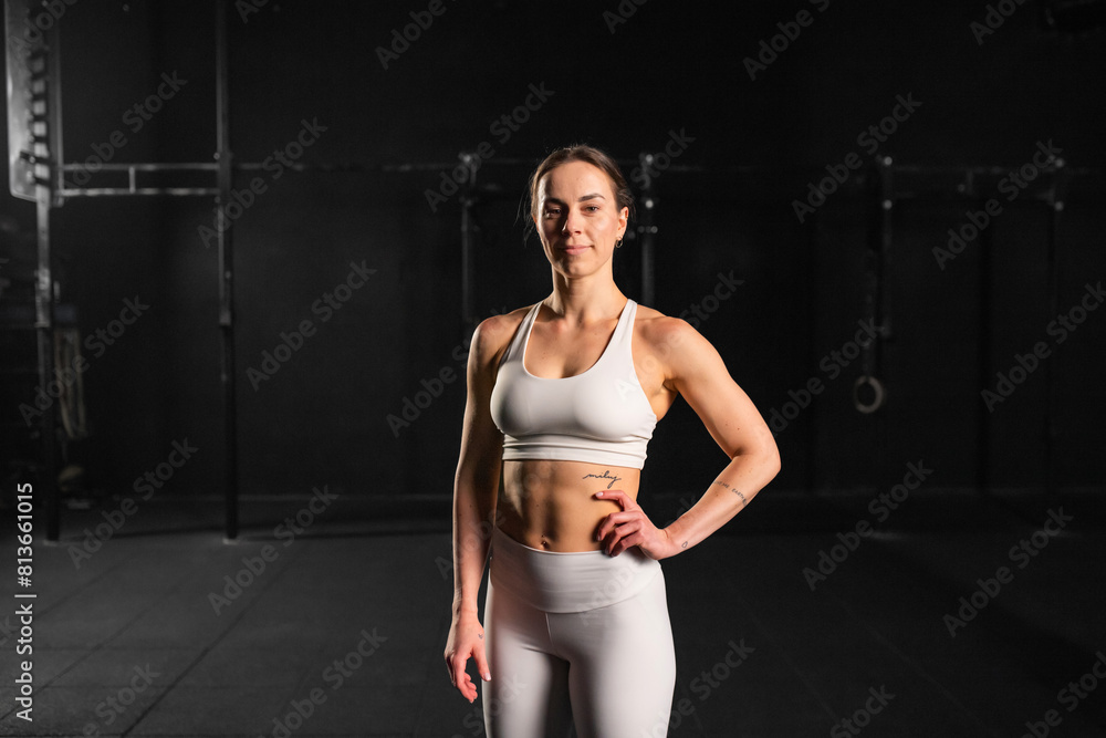Obraz premium Portrait of young muscular woman in gym. Routine workout for physical and mental health.
