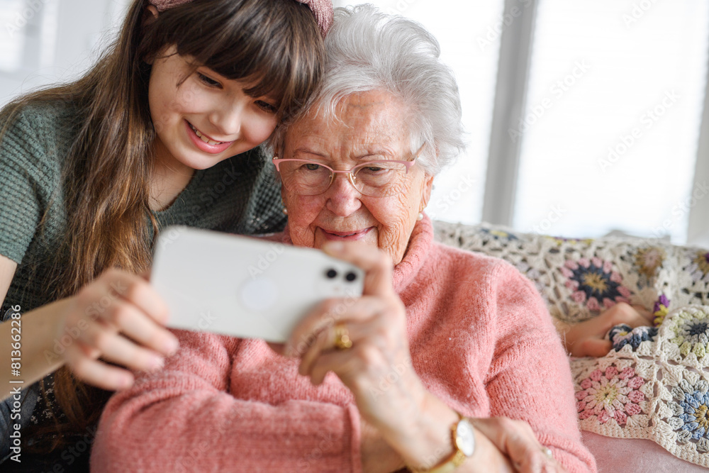 Grandmother with cute girl taking selfie with smartphone. Portrait of an elderly woman spending time with granddaughter. Grandmother with cute girl taking selfie with smartphone. Portrait of an elderly woman spending time with granddaughter.