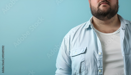 Overweight man in tight shirt on light blue background, closeup © Oleksiy