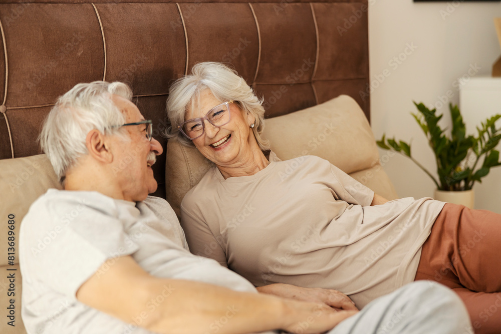 Affectionate senior couple laying down in a bedroom and laughing. Affectionate senior couple laying down in a bedroom and laughing.