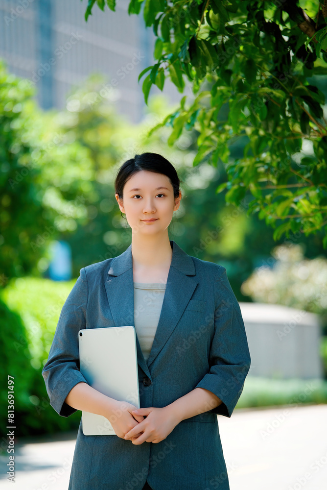 Confident Businesswoman Holding Laptop in Urban Setting Confident Businesswoman Holding Laptop in Urban Setting