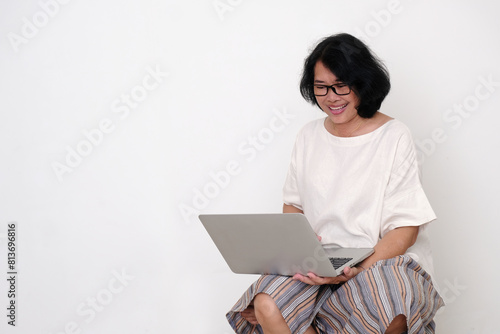A woman is using a laptop to get connected with others; smiling, happy expression photo
