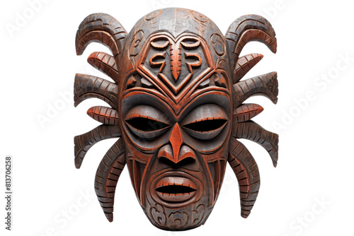A carved wooden mask with a spidery face and horns. The mask is brown and has a creepy, menacing look to it