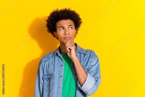 Photo of nice young man look empty space wear denim shirt isolated on yellow color background © deagreez