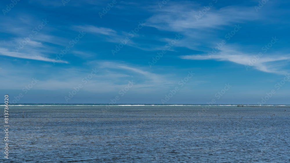 Endless turquoise ocean and blue sky with clouds. Foaming waves are visible on the horizon. Minimalistic seascape. Philippines.