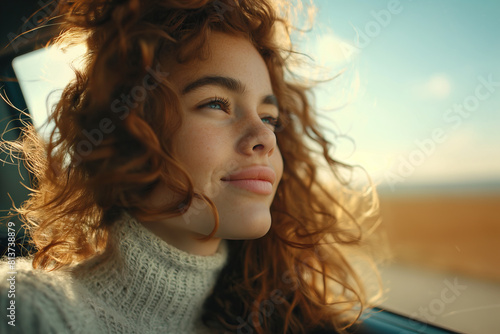 Beautiful young woman driving her new car at sunset. Woman in car. Close up portrait of pleasant looking female with glad positive expression, woman in casual wear driving a car © Frenchiebuddha