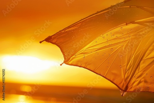 Single beach umbrella partially open with billowing fabric at sunset