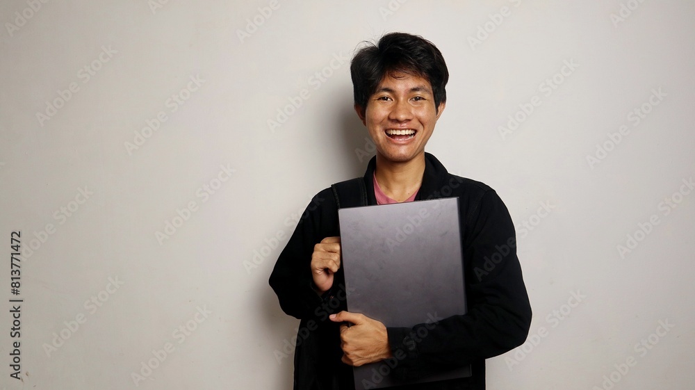 college young asian man happy while carrying bag and holding laptop college young asian man happy while carrying bag and holding laptop