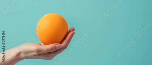 Notion of stress aversion procedure in-depth of an individual's hand holding a lightly-held orange stress ball over a pale blue setting and space, Generative AI. photo