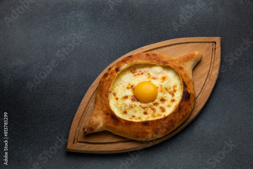 Georgian khachapuri with egg yolk on wooden board