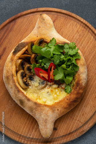 Traditional georgian khachapuri with mushrooms and cheese on a wooden board
