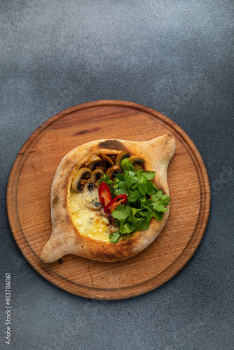 Traditional georgian khachapuri with mushrooms and cheese on a wooden board
