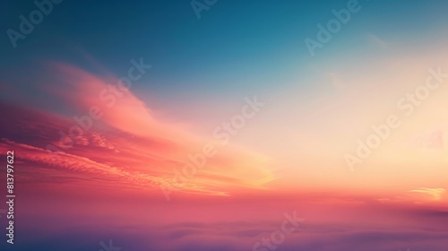 A serene sky painted with a gradient of orange and blue hues as the sun sets, with soft clouds. © Prostock-studio