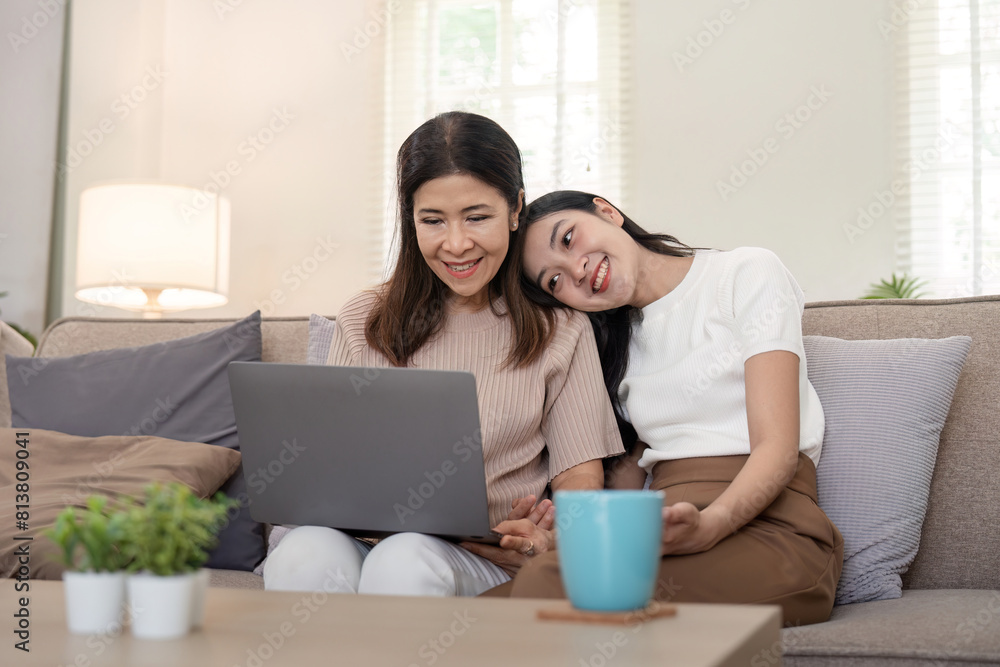 Happy mother and adult daughter use laptop having fun, sitting on couch at home, smiling woman embracing older mum, spending leisure time together. for Happy mother's day Happy mother and adult daughter use laptop having fun, sitting on couch at home, smiling woman embracing older mum, spending leisure time together. for Happy mother's day
