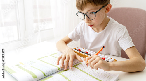 Boy doing mental arithmetic on abacus at school photo