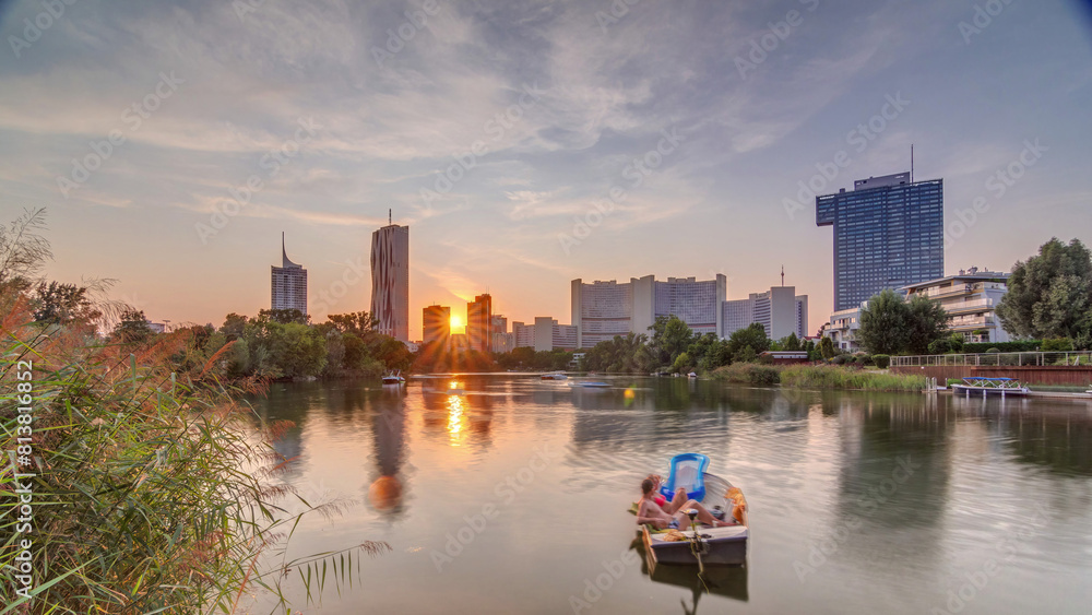 Fototapeta premium Sunset over Vienna international center skyscrapers with Kaiserwasser lake reflection view timelapse